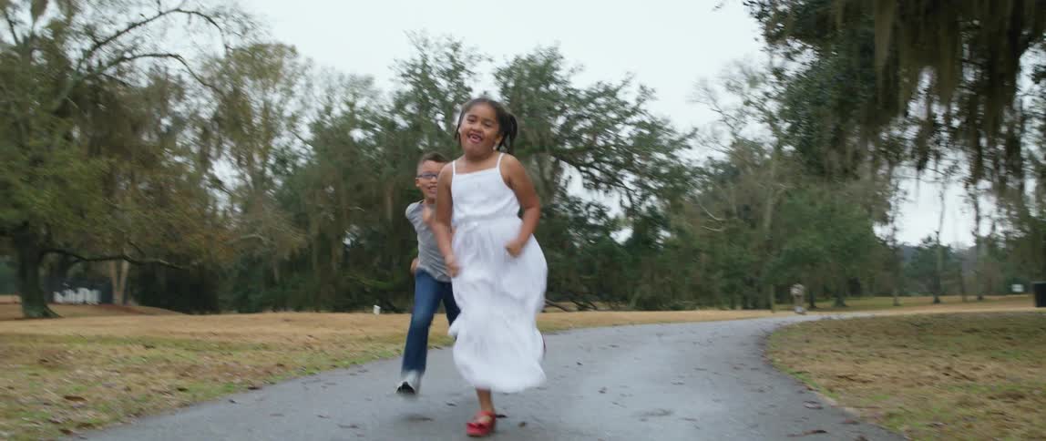 Happy kids racing each other running on a path in a park at daytime