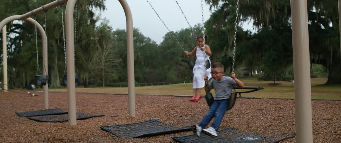Children swinging on a playground in the park at daytime