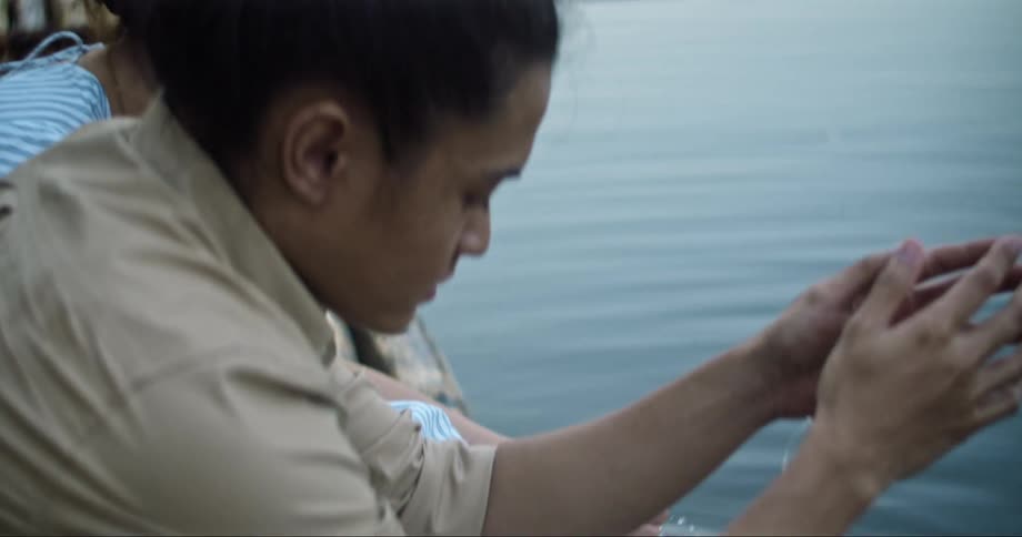 Man and woman sit next to each other on dock with feet in lake