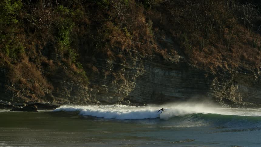 Surfer wearing black wetsuit is riding a wave