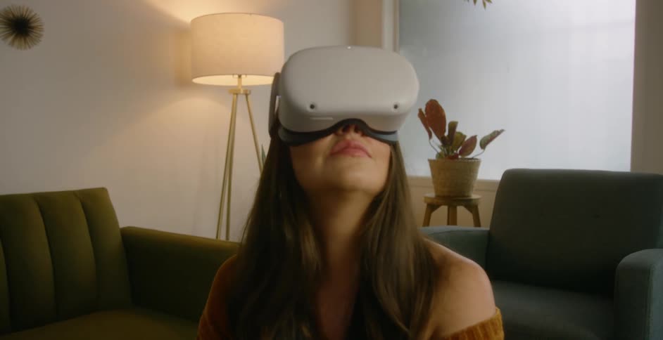 Woman sitting on the living room at home wearing virtual reality goggles