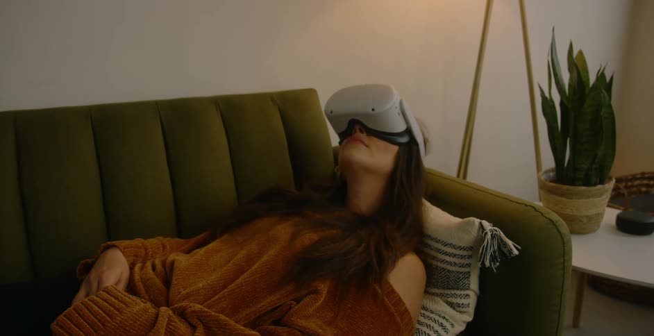 Woman wearing vr goggles lies on back on sofa moving head around