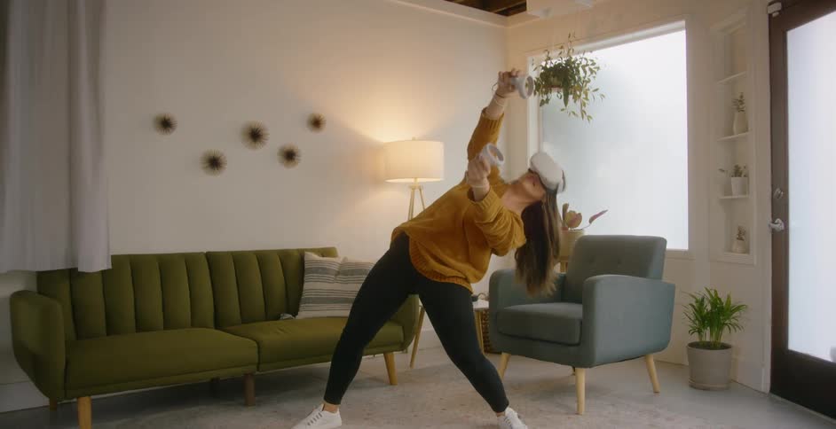 Woman with a brown sweater black leggings and white shoes uses virtual reality headset in the living room at home