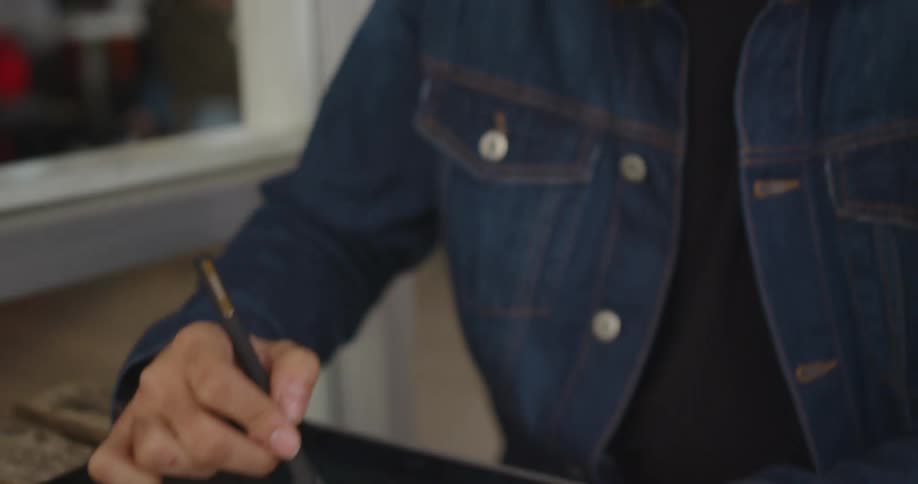 A man with glasses drawing on a tablet with a stylus