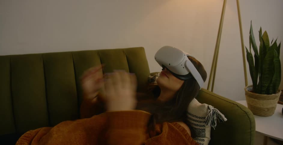 A woman puts on virtual reality glasses and lies down on a couch