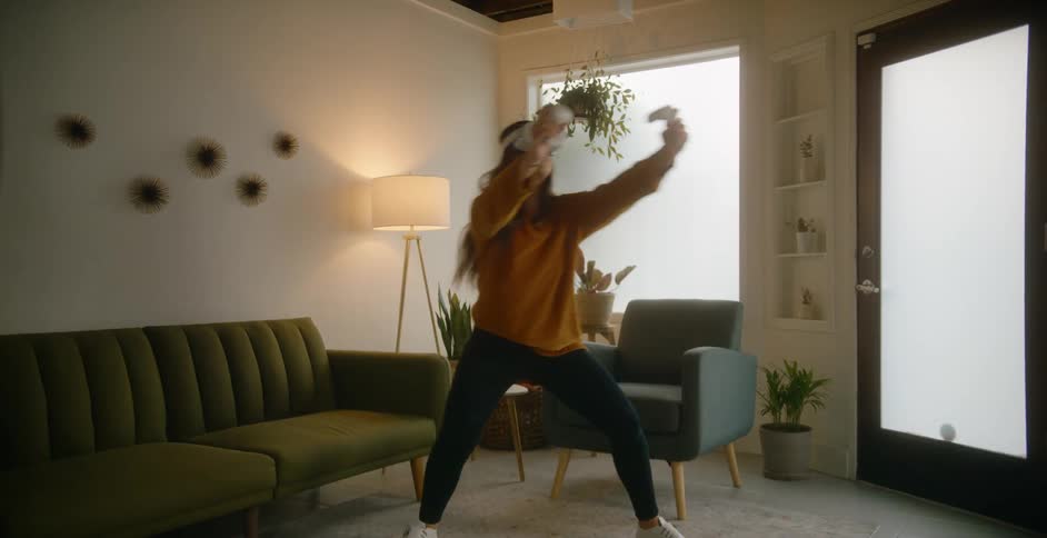 A woman dances in place in her living room while using a virtual reality headset