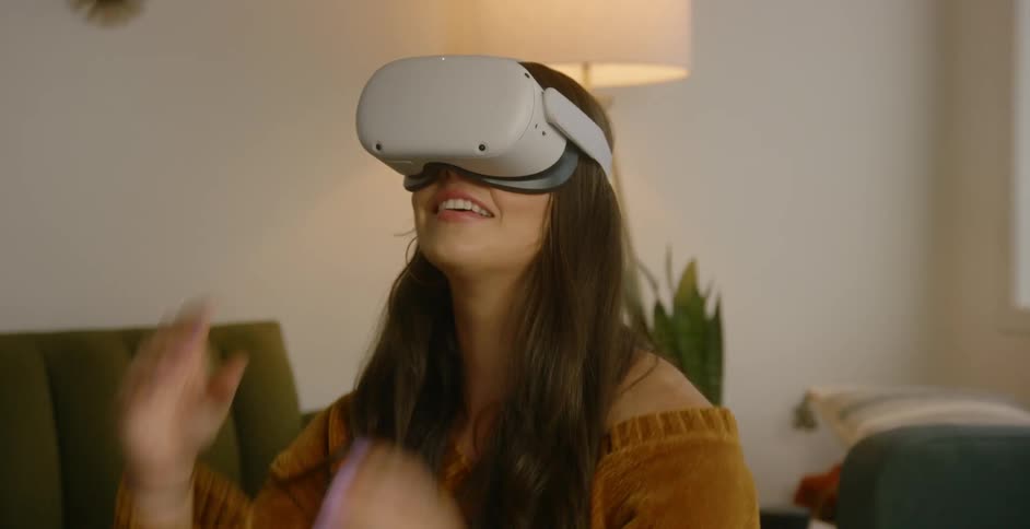Woman dons vr headset and looks around smiling while sitting on couch near lamp