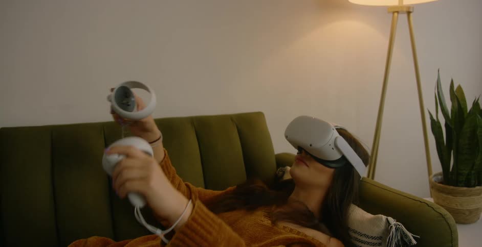 A woman using avirtual reality headset while lying on a living room sofa