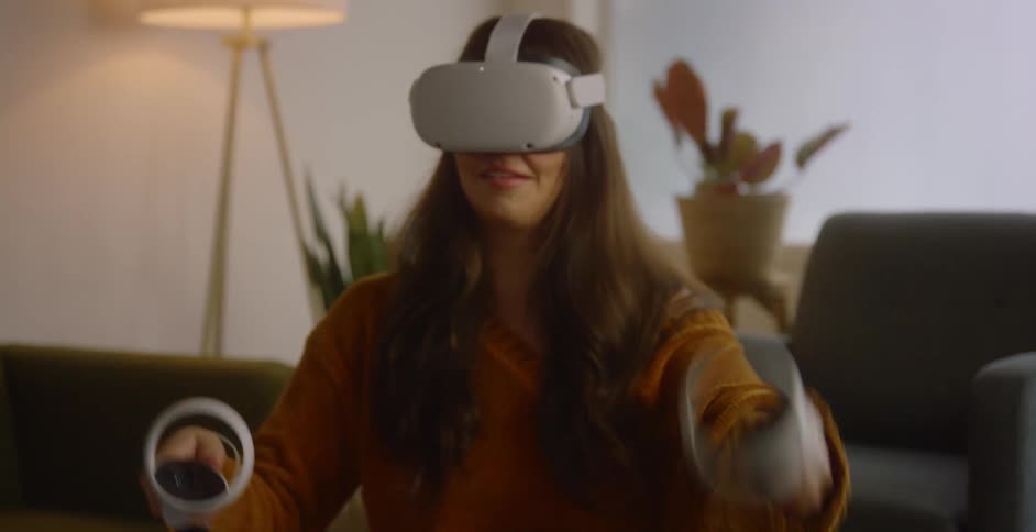 A woman using a virtual reality headset while sitting on a living room floor