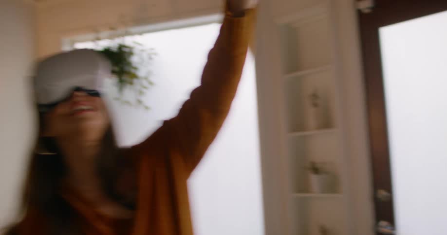 A woman plays a game using a virtual reality headset in the living room of a house during the day