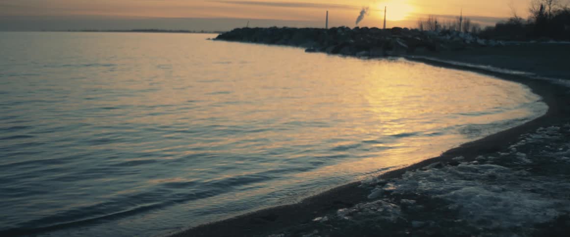 Water flowing towards a shoreline on a beach at sunset