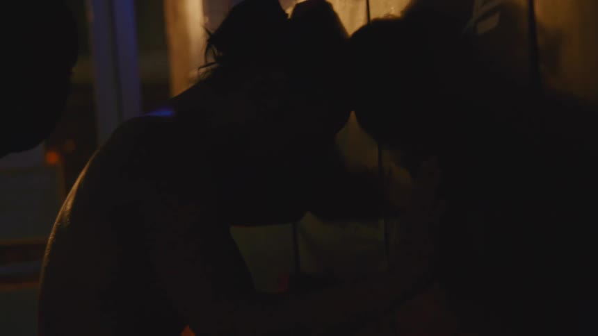 Tired shirtless young man reclined against a wall on a store at night