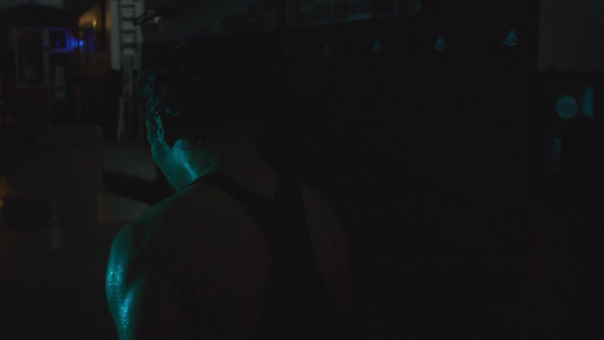 A woman covered in sweat walks through a dark room