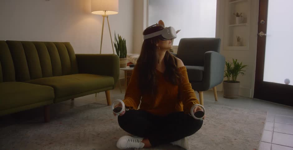 Woman wearing vr goggles sits cross legged on rug in living room