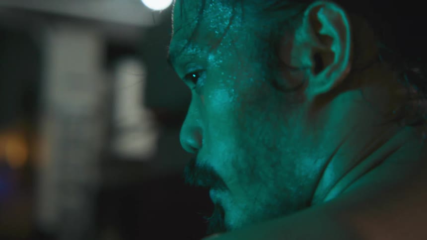 A man is standing in a room at night and is sweating