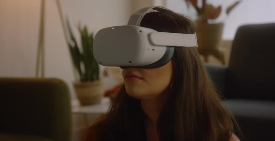 A woman in a room with a virtual reality headset with a wall and window in the background