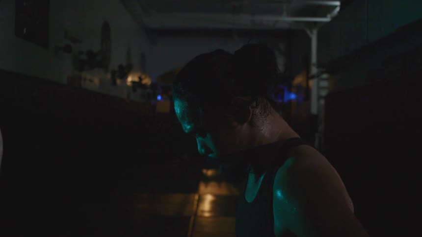 Sweating man paces near speed bag in dimly lit gym
