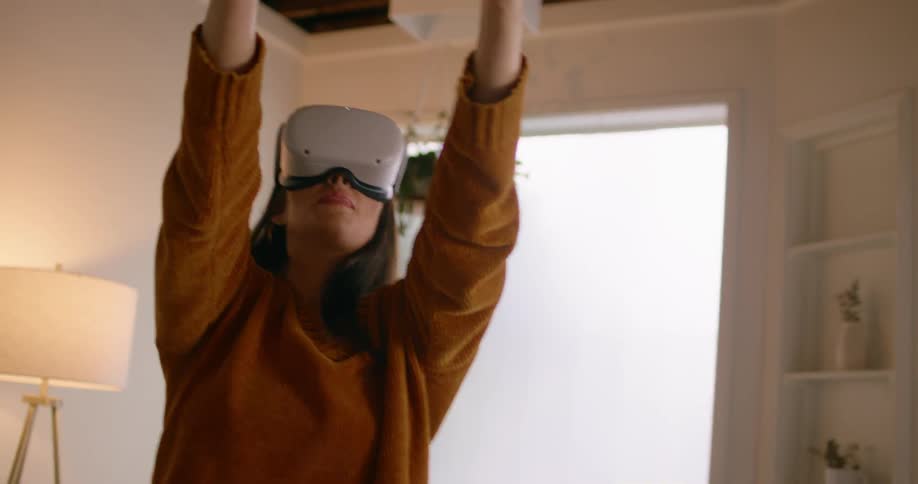 A woman holds both hands in the air as she plays a virtual reality game