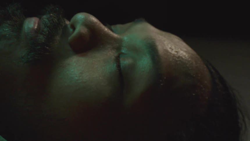 Man with a beard and long hair lying down on the ground closes his eyes