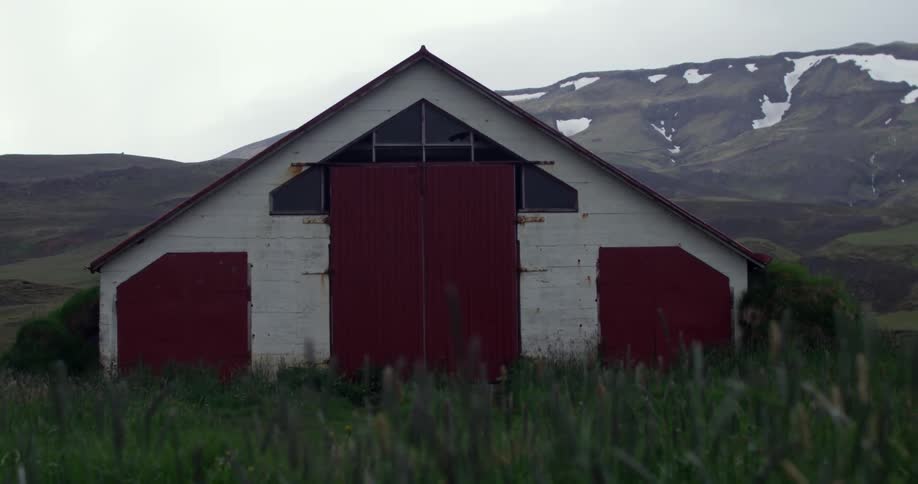 A barn in a field near some hills