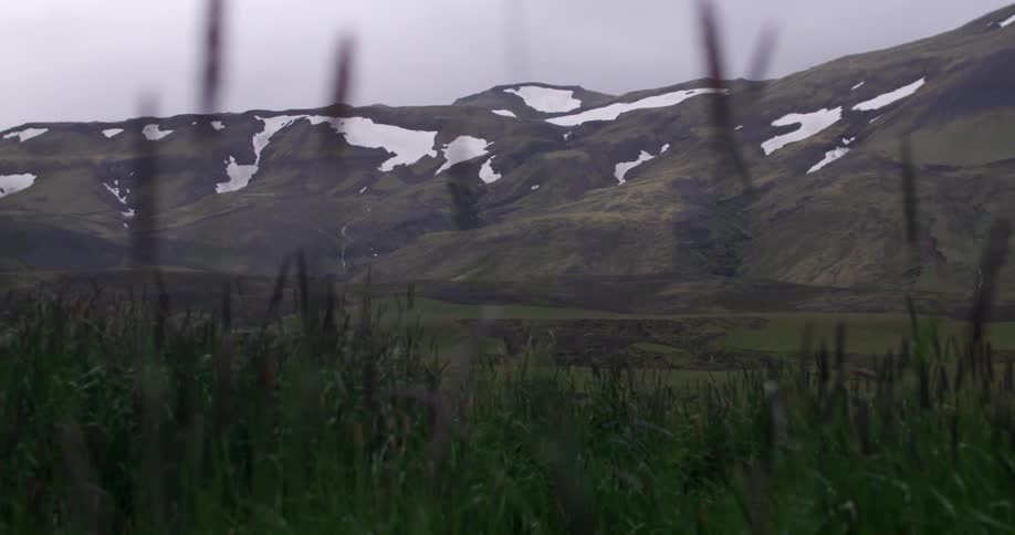 A mountain as seen from a nearby grass field on a winter day