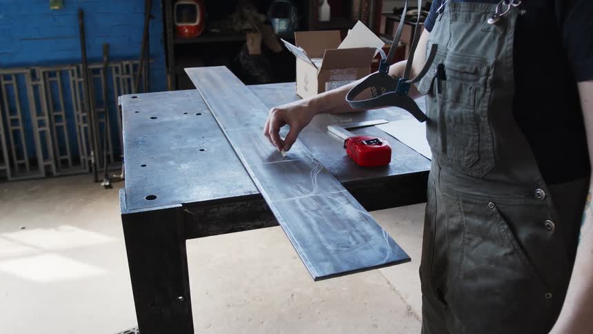 A woman in a shop draws on a plank of wood