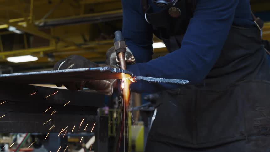 An employee cutting metal in a shop