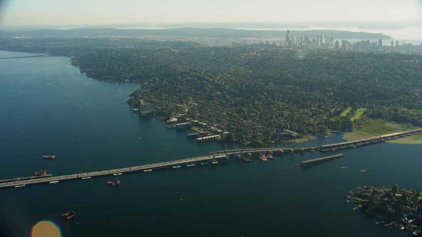 An aerial view of bridge spanning a body of water with skyscrapers in the distance