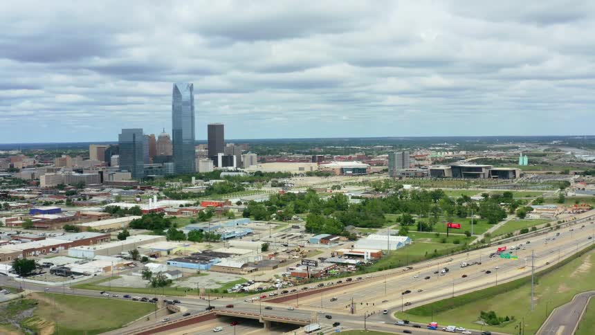 Aerial view of cars driving on a highway next to the city is displayed