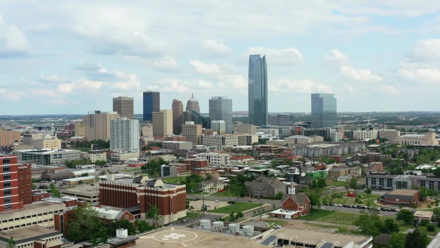 A city with buildings and trees with the sky and clouds in the background