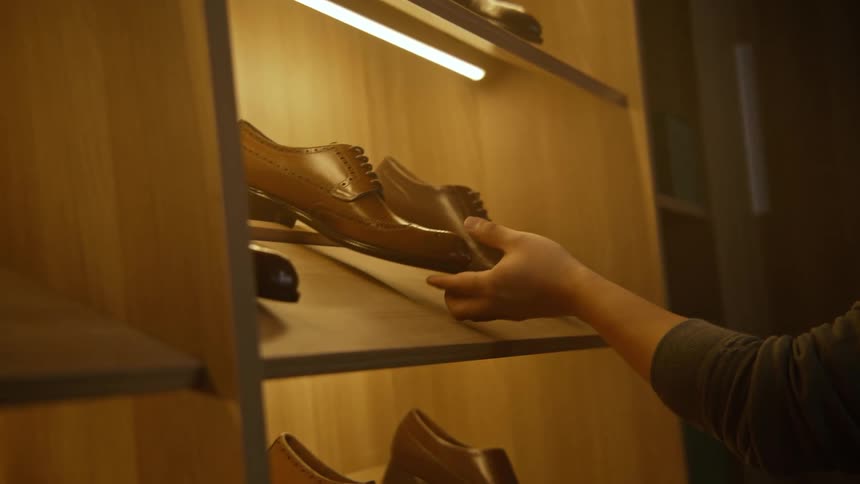 A man in a store grabbing a shoe off a shelf