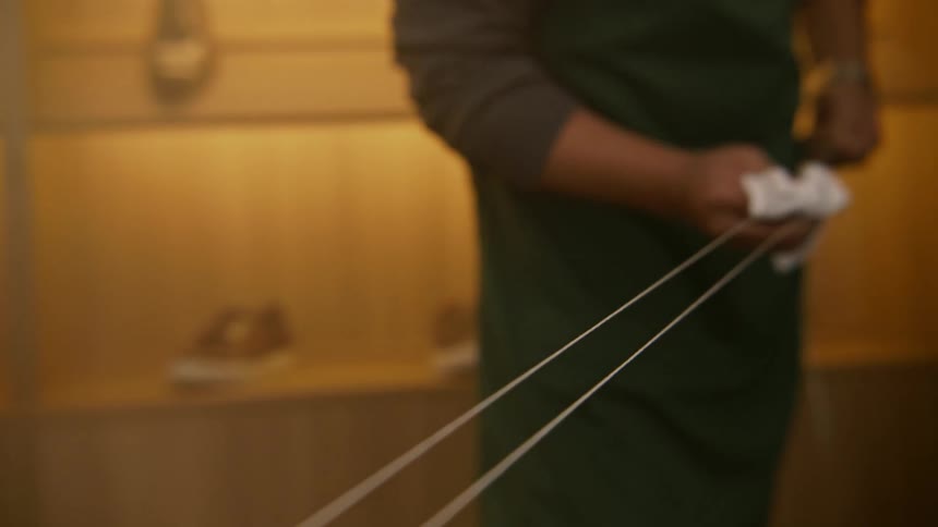 A person in a shoe store cleaning strings with a cloth with shelves and shoes in the background