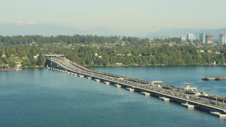 Aerial view of traffic driving over a bridge on a river next to the city skyline