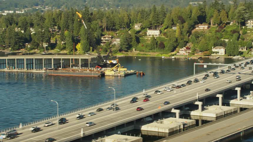 A long bridge with heavy automobile traffic spans a large waterway
