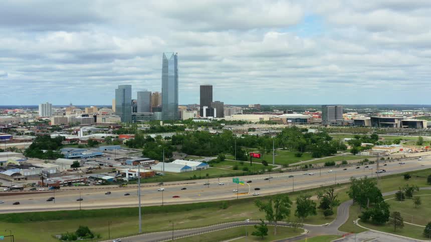 An aerial view of cars driving on a highway in front of a downtown city skyline