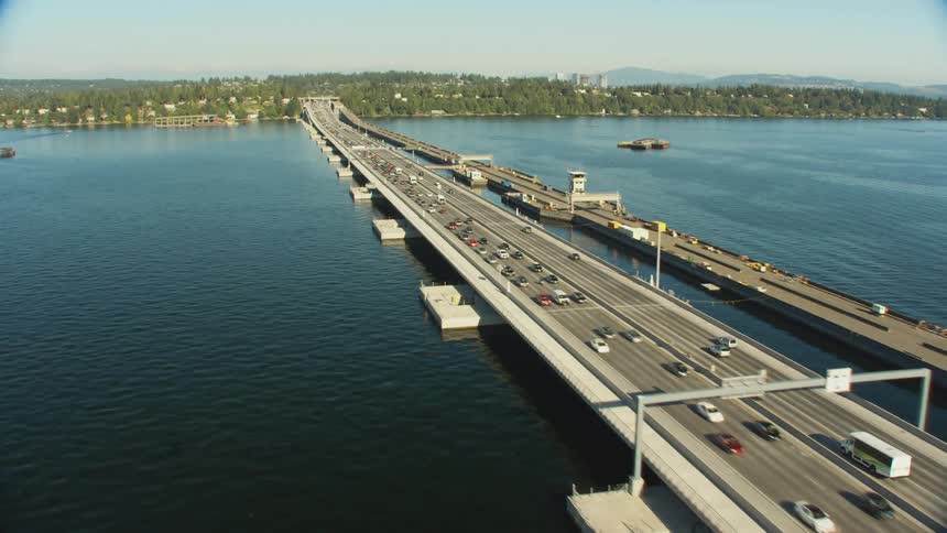 Cars and buses travel on a bridge heading to and from the shore