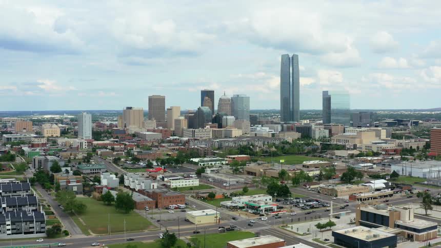 A city with buildings and trees with the sky and clouds in the background