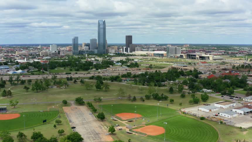 A city skyline stands tall in the distance beyond parks and roadways