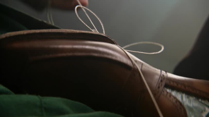 A shoemaker lacing string through a leather shoe