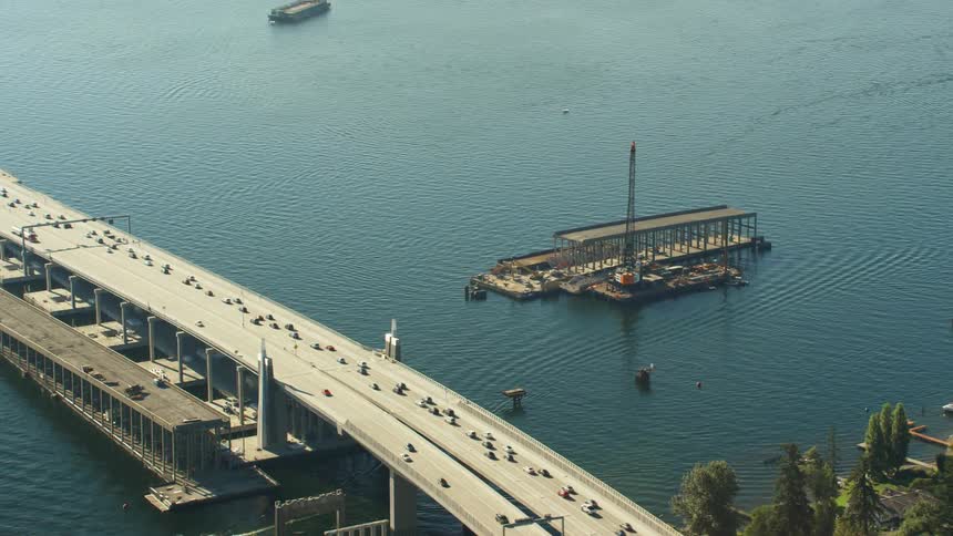 An aerial view of cars driving across a bridge and boats in the water