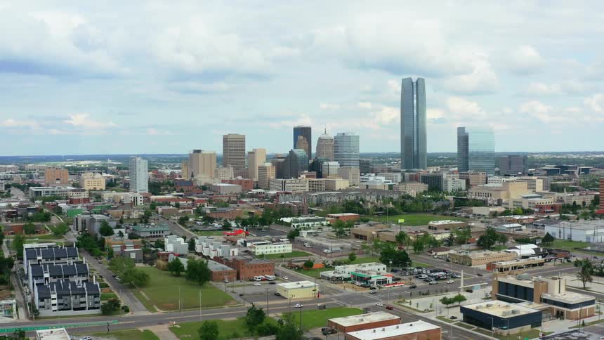A city with buildings and trees with the sky and clouds in the background