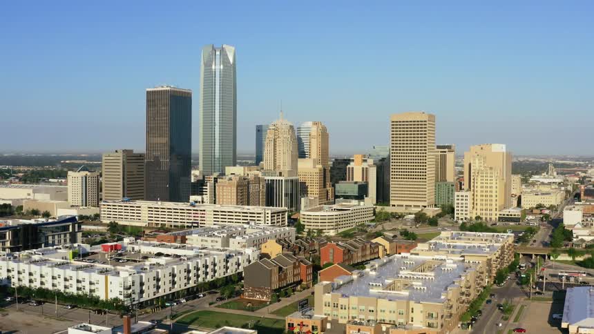 A city with buildings and trees with the sky and clouds in the background
