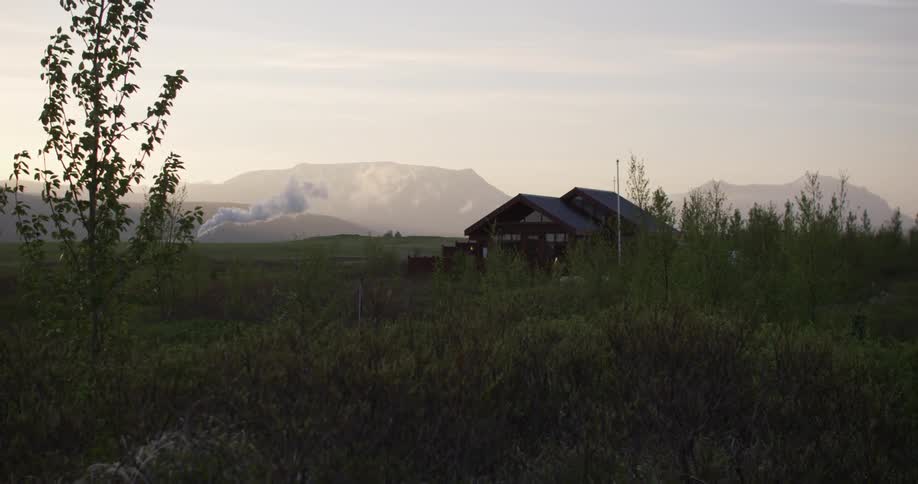A single home sits on a green field on a cloudy day