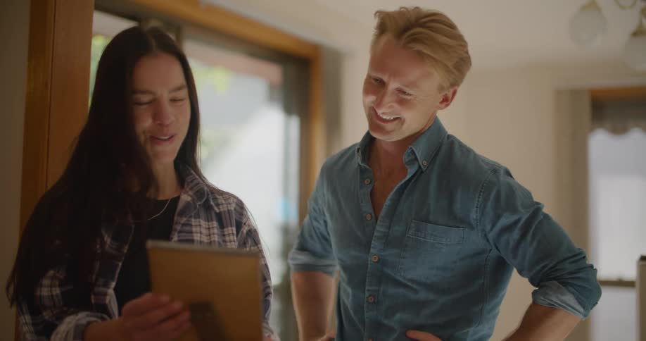 A couple move into a new home and stop to reminisce over a framed photograph
