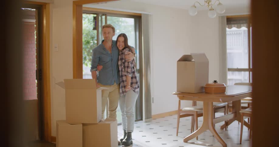 A man and woman moving boxes into a house
