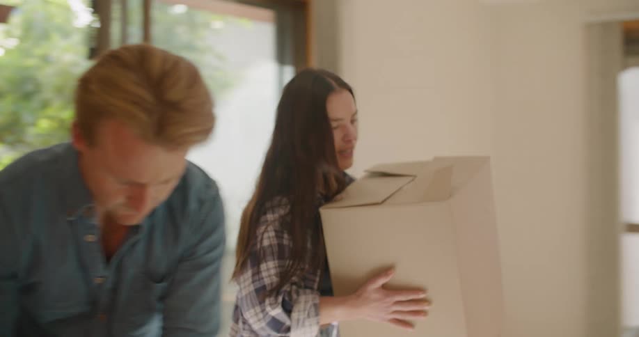 A man and woman move into their new home and hug while unpacking boxes