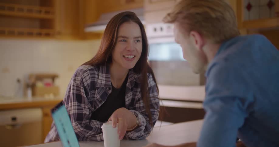 A man and woman look at a laptop in the kitchen