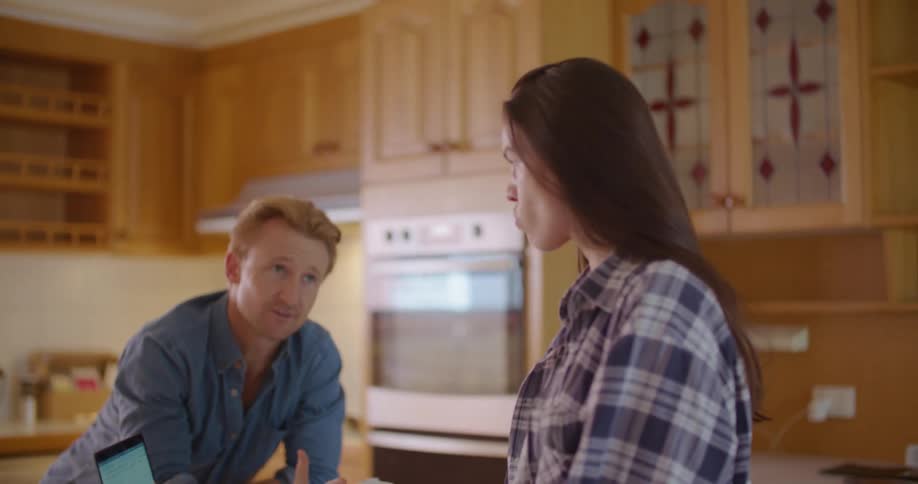 Young couple talking around a laptop on the kitchen at home