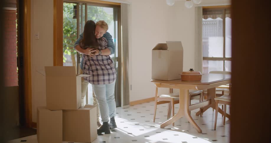 Young happy couple celebrate moving to a new house with a hug