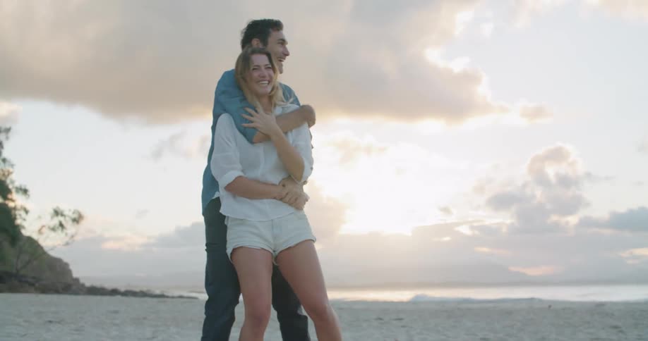 A man and woman are hugging on the beach